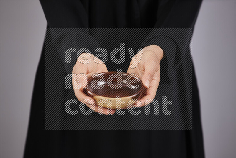 A woman in black abaya holding different wooden essentials in different positions