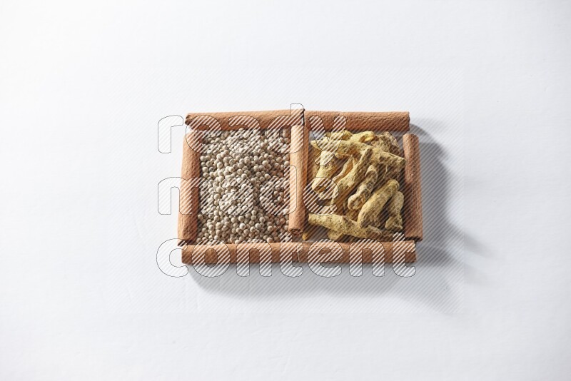 2 squares of cinnamon sticks full of white pepper and turmeric fingers on white flooring