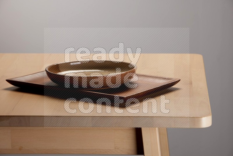 multicolored plate on a rectangular wooden tray on the edge of wooden table