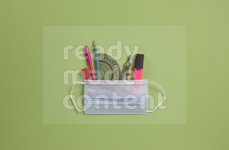Different school supplies on green background