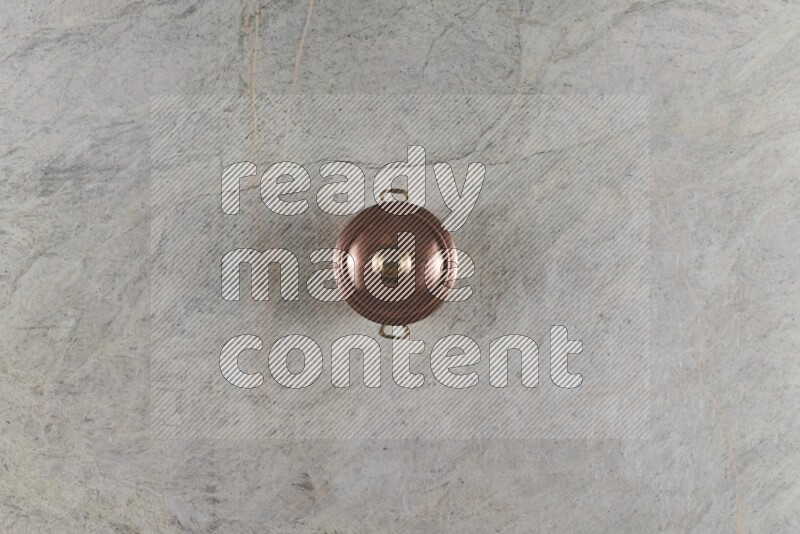 A small copper pot on grey marble background