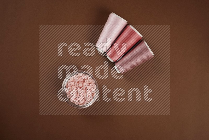 Pink sewing supplies on brown background