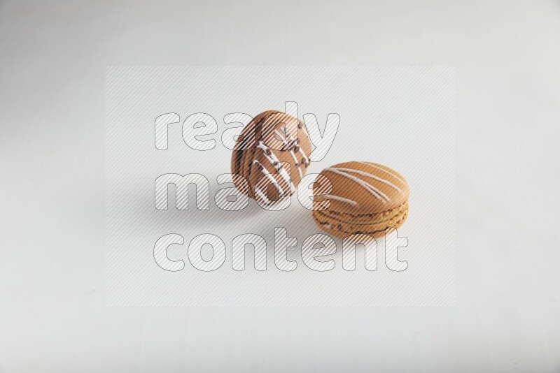 45º Shot of of two assorted Brown Irish Cream, and Brown white Chocolate Caramel macarons on white background