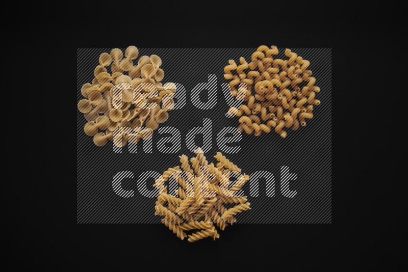 Different pasta types in bunches on black background