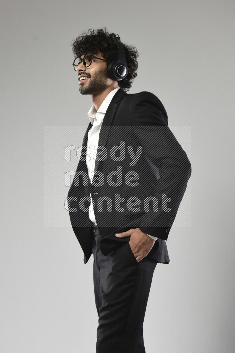 A man wearing formal standing and putting on headphones on white background