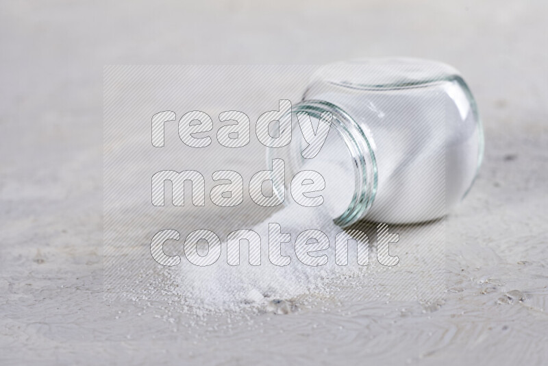 A glass jar full of fine table salt on white background