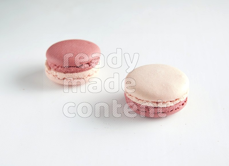 45º Shot of two Pink Litchi Raspberry macarons on white background