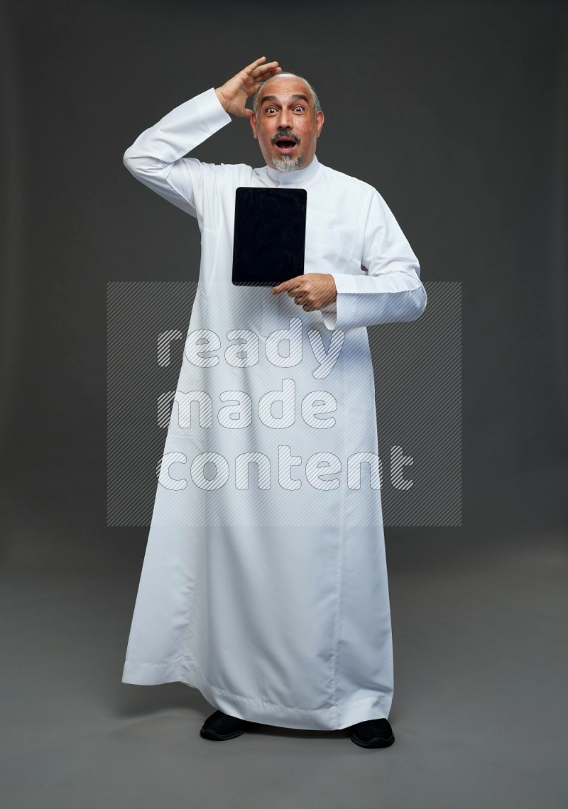 Saudi man without shomag Standing working on tablet on gray background