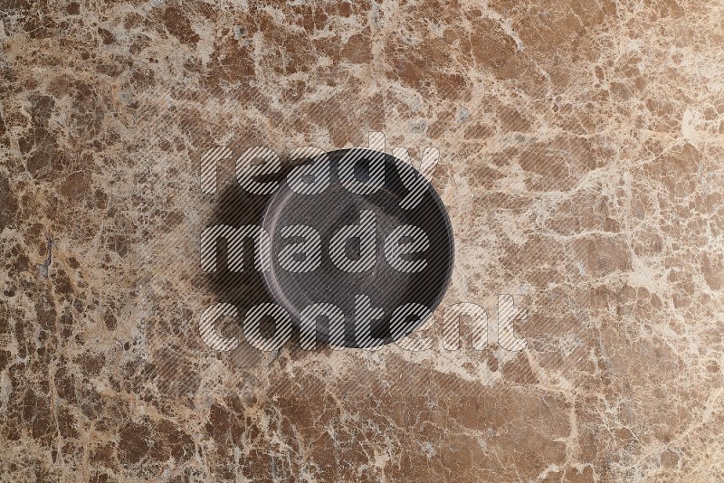 Top View Shot Of A Black Pottery Oven Plate On beige Marble Flooring