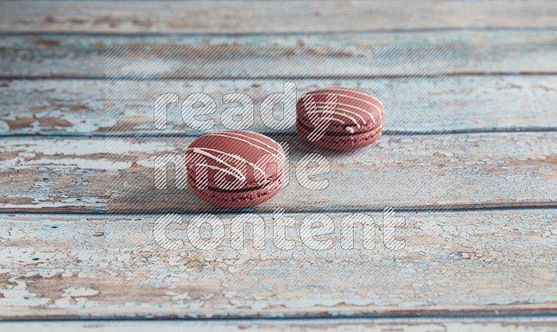 45º Shot of two Red Poppy Flower macarons on light blue wooden background