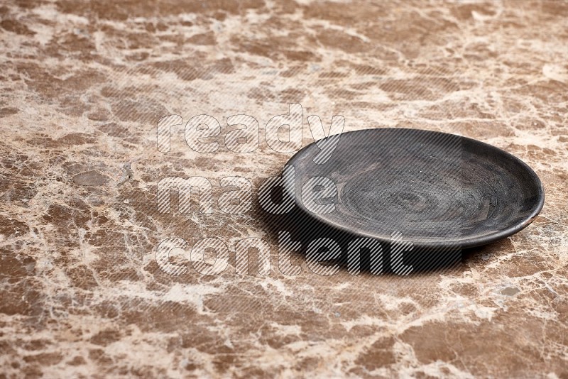 Black Pottery Plate on Beige Marble Flooring, 45 degrees