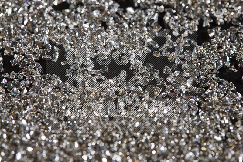 Silver shimmering fragments of glass scattered on a black background