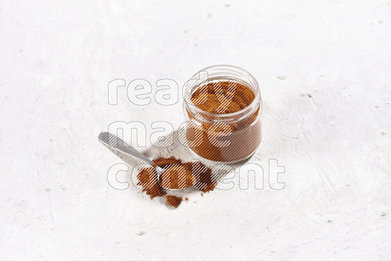 A glass jar full of ground paprika powder on white background