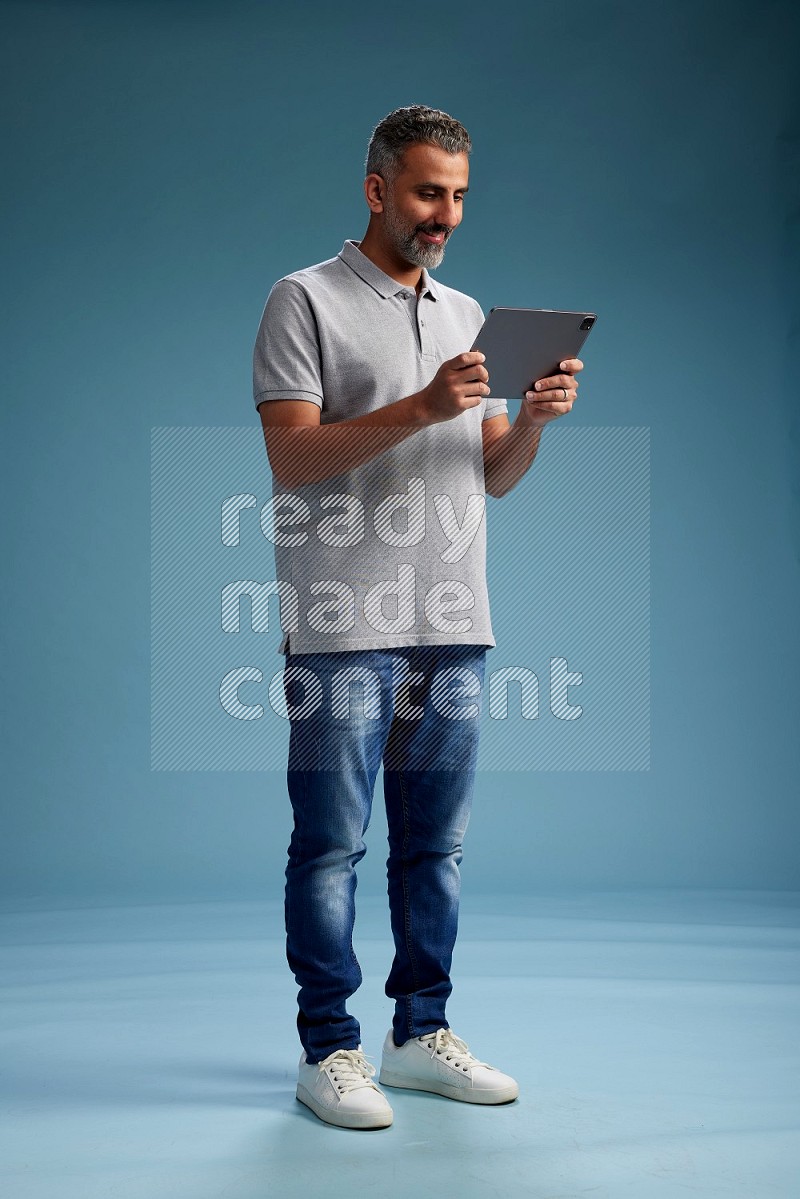 Man Standing working on tablet on blue background