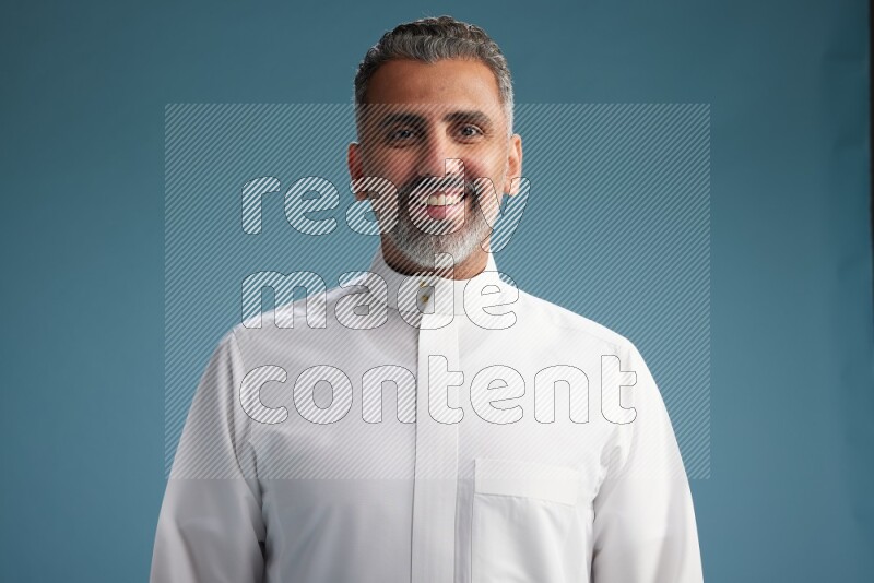 Saudi man waring thob posing to the camera on blue background
