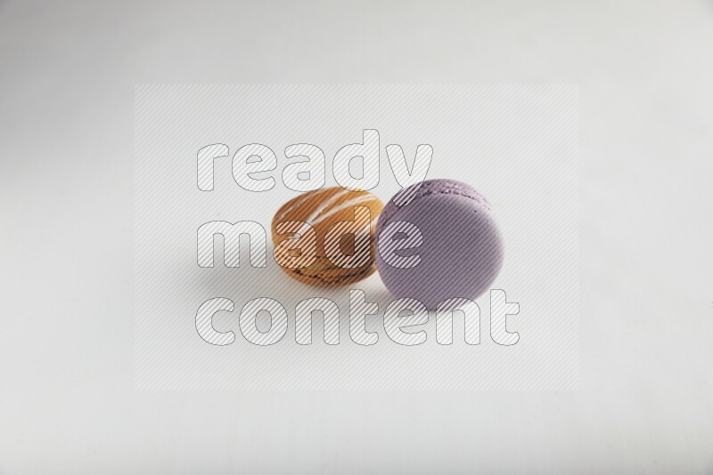 45º Shot of of two assorted Brown Irish Cream, and Purple Blueberry macarons on white background