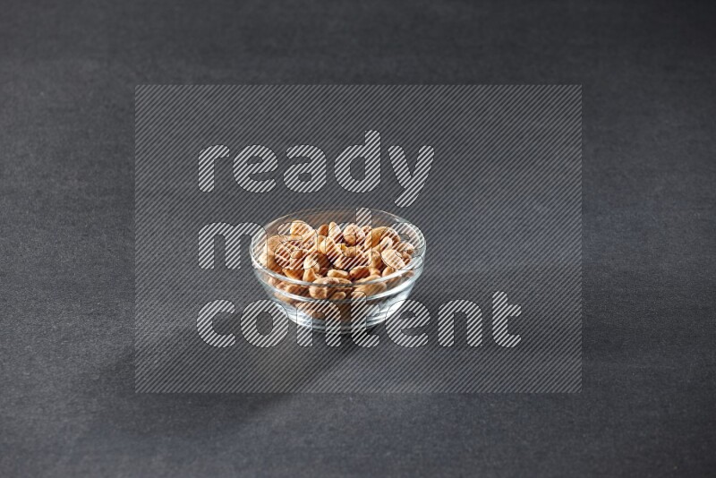 A glass bowl full of cashews on a black background in different angles