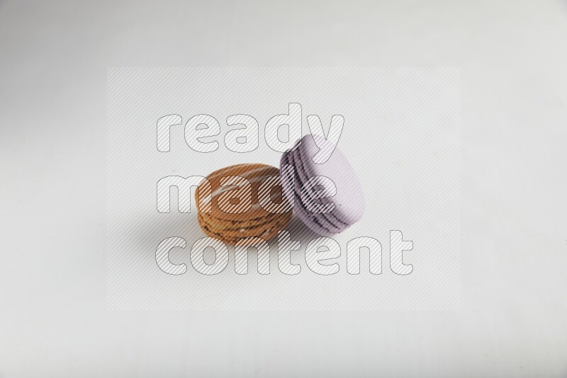 45º Shot of of two assorted Brown Irish Cream, and Purple Blueberry macarons on white background