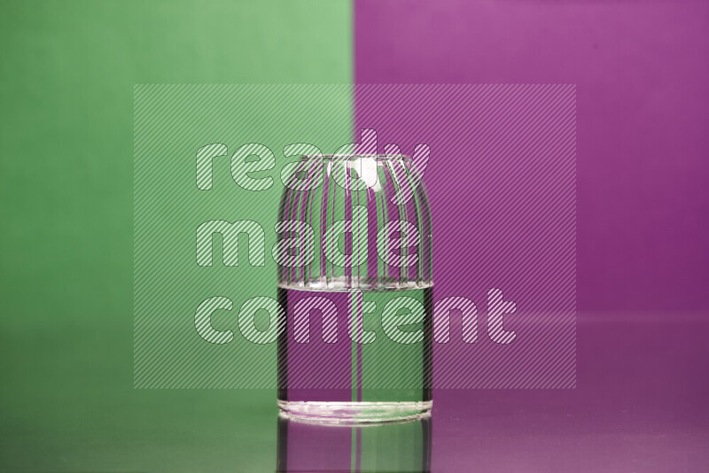 The image features a clear glassware filled with water, set against green and purple background