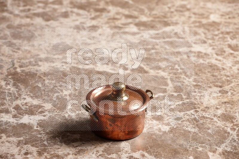 A small copper pot on beige marble background