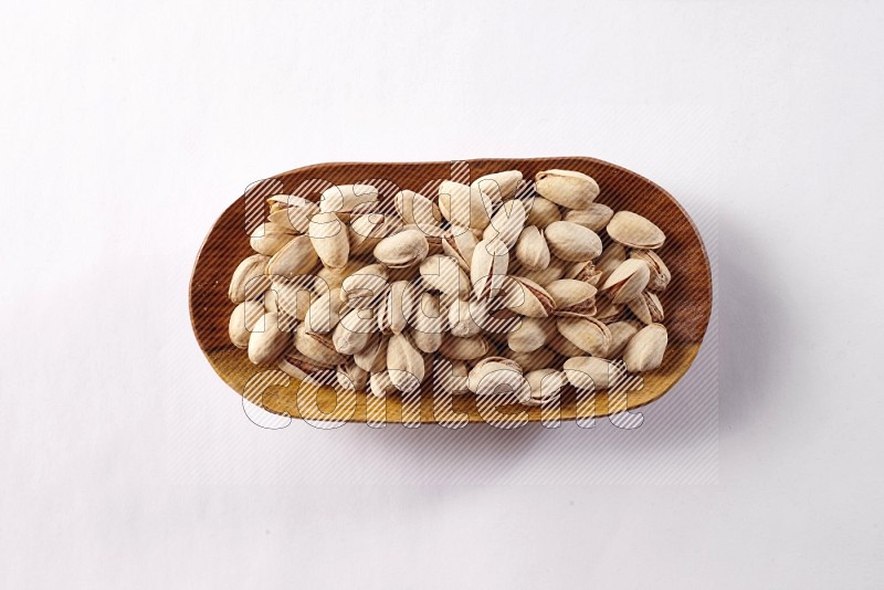 Pistachios in a wooden plate on white background
