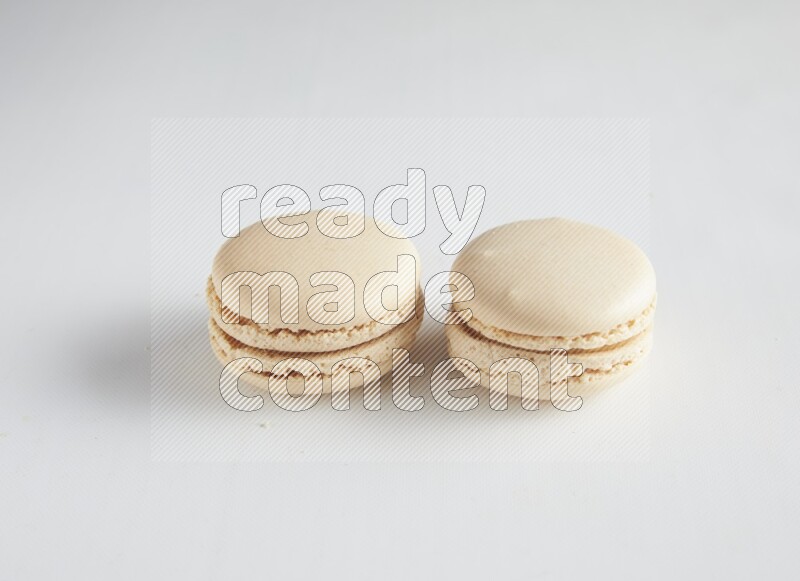 45º Shot of two White Caramel fleur de sel macarons on white background