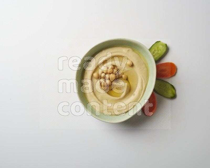 Hummus in a green plate garnished with roasted chickpeas  on a white background