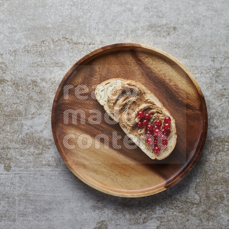 open faced peanut butter sandwich with cranberries and chia seeds grey textured background