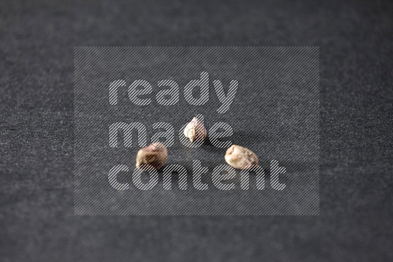 3 peeled pistachios on a black background in different angles