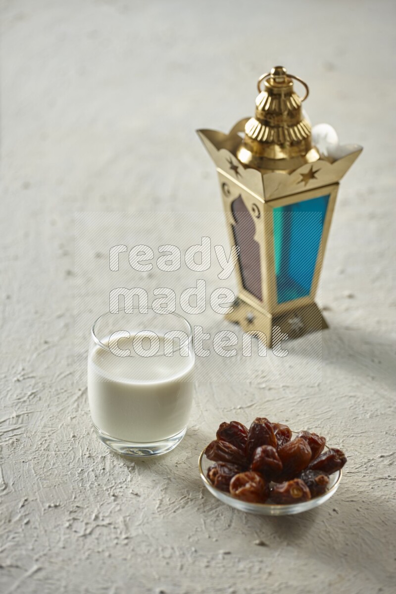 A golden lantern with different drinks, dates, nuts, prayer beads and quran on textured white background