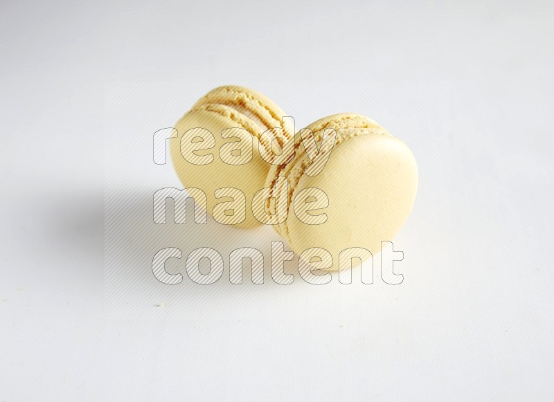 45º Shot of two Yellow Vanilla macarons on white background