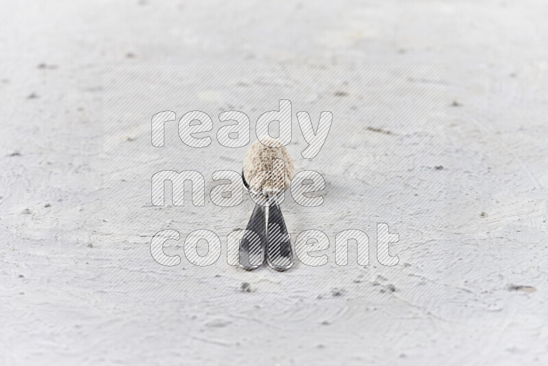 Two metal spoons full of onion powder on white background