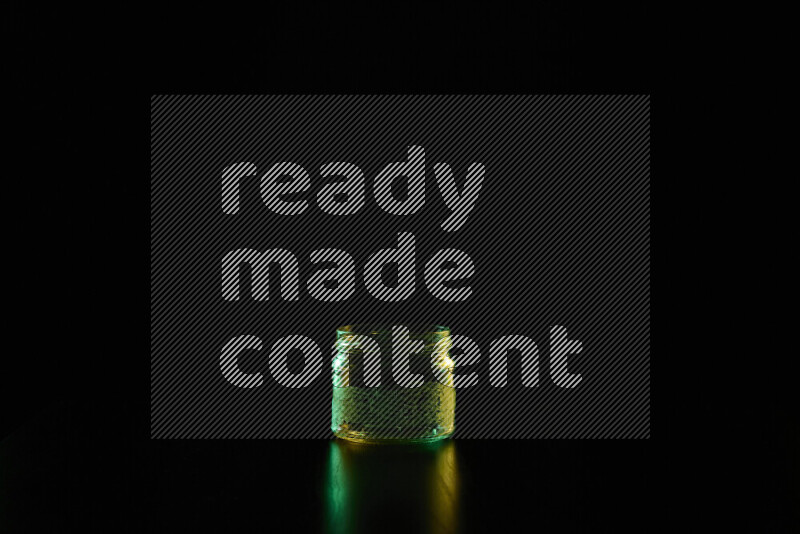 Glassware with rim light in green and yellow against black background