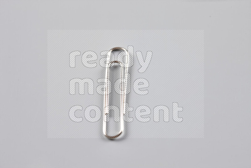 Silver paper clips isolated on a grey background