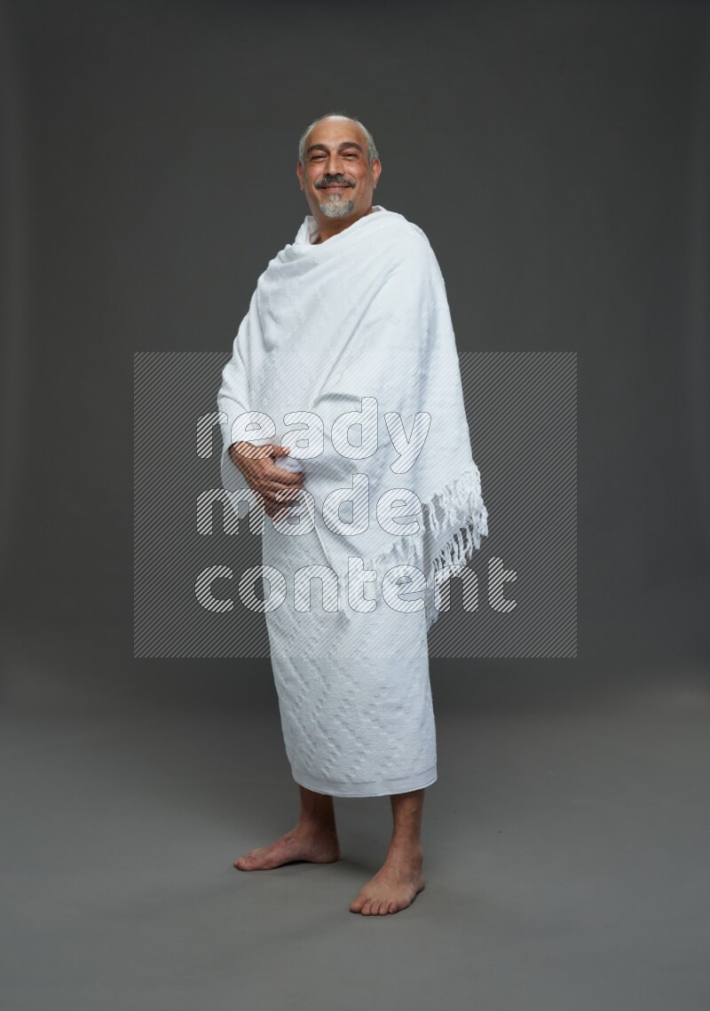 A man wearing Ehram Standing Interacting with the camera on gray background