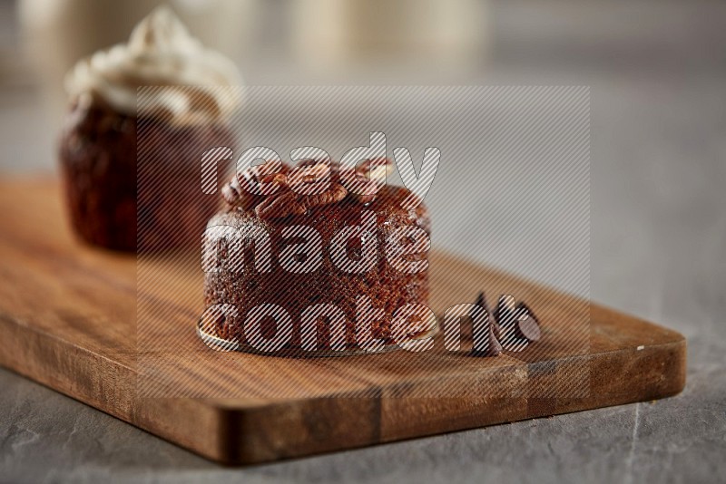 Chocolate cupcake topped with pecan on a wooden board