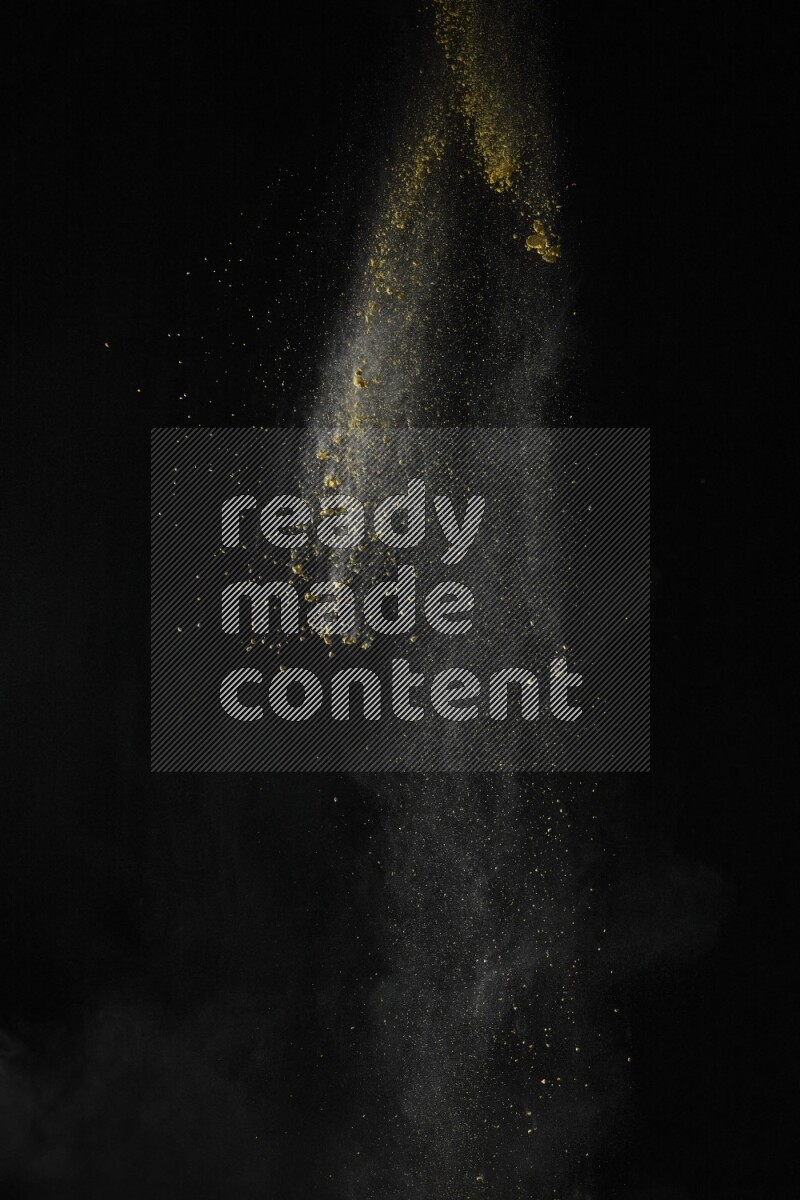 A side view of yellow powder explosion on black background