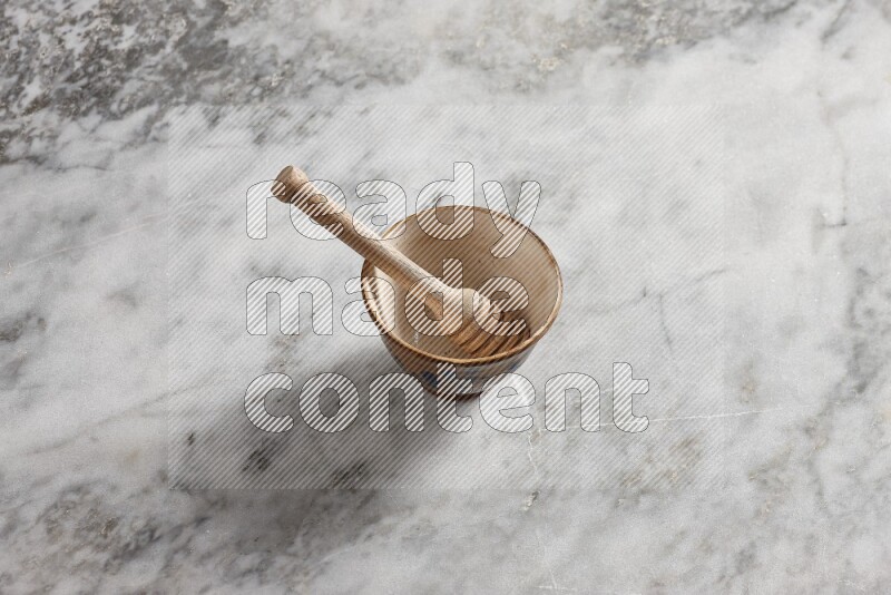 Decorative pottery bowl with wooden honey dipper in it on grey marble background
