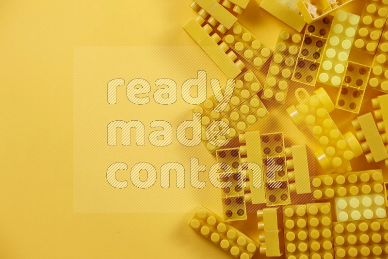 Yellow plastic building blocks on yellow background in top view (kids toys)