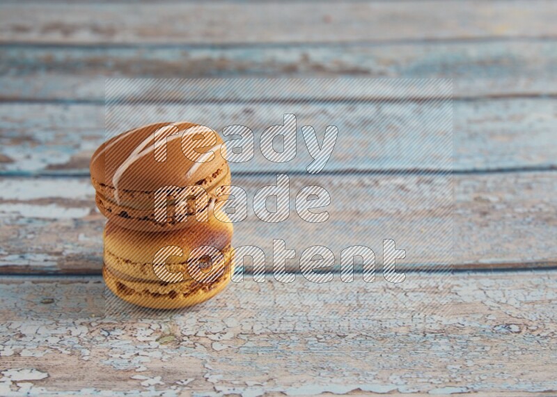 45º Shot of of two assorted Brown Irish Cream, and Yellow Crème Brulée macarons on light blue background