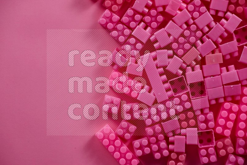 Pink plastic building blocks on pink background in top view (kids toys)