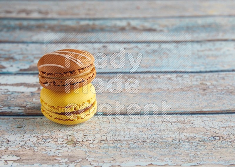 45º Shot of of two assorted Brown Irish Cream, and Yellow Lemon macarons on light blue background