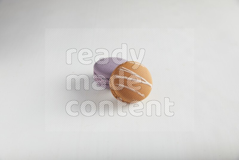45º Shot of of two assorted Brown Irish Cream, and Purple Blueberry macarons on white background