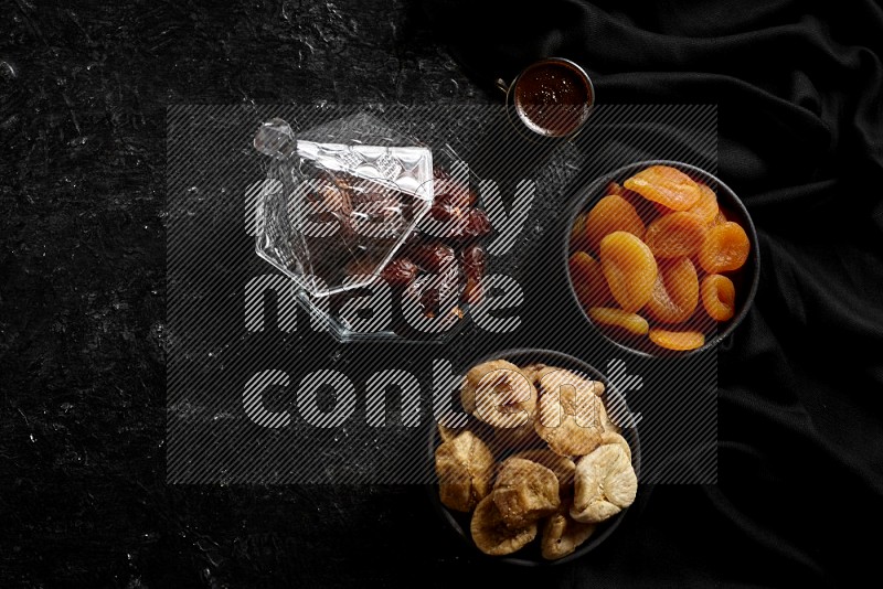 Dates in glass bowl with coffee and dried fruits in a dark setup