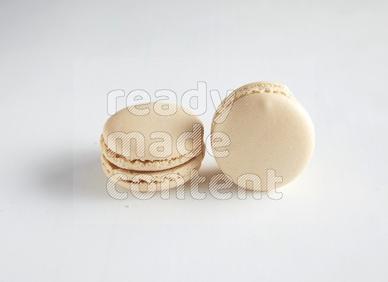 45º Shot of two White Caramel fleur de sel macarons on white background