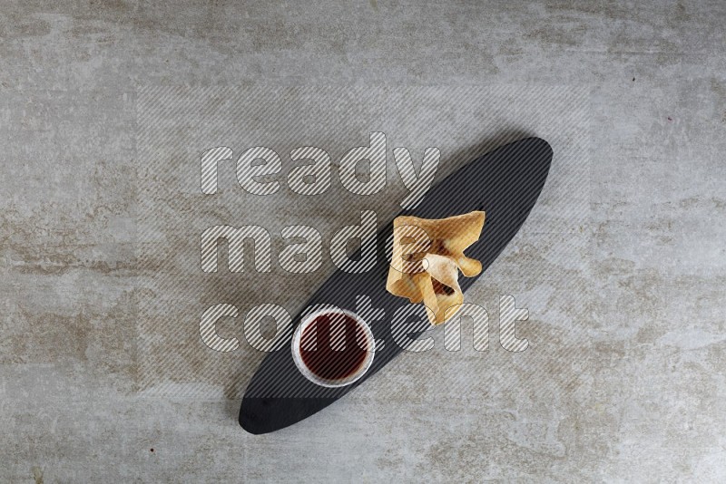 wonton cups with soy sauce ramkin on oval slate on grey textured counter top