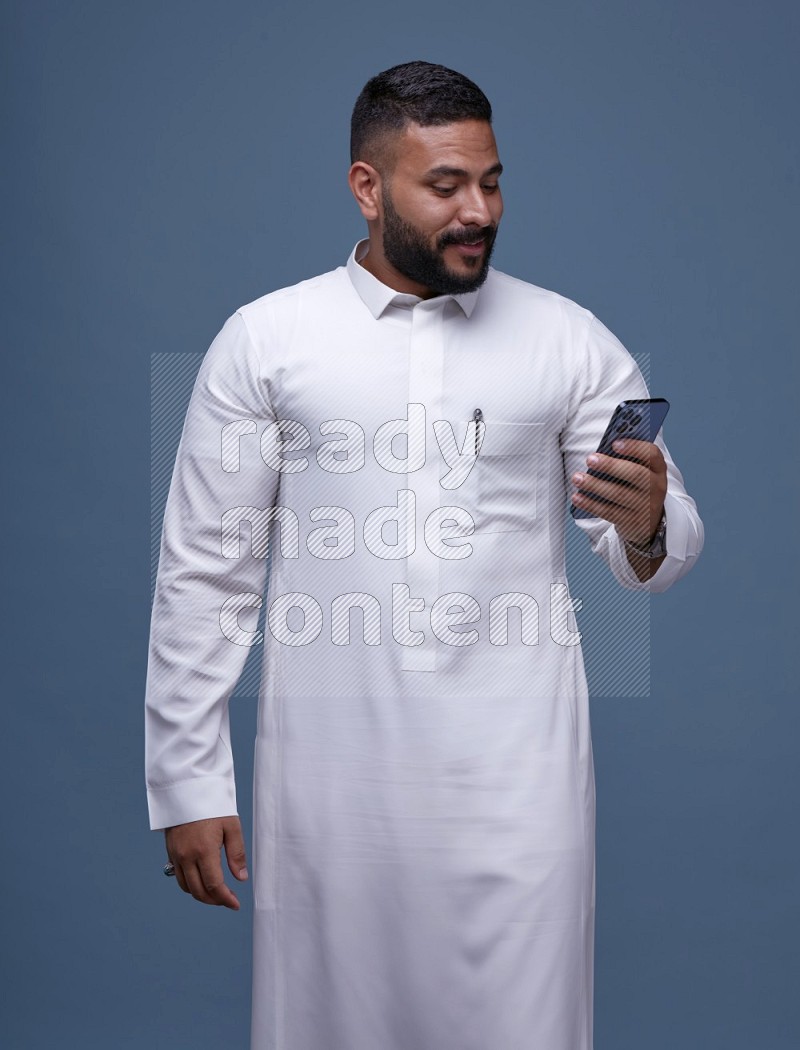 A man Texting on Blue Background wearing Saudi Thob