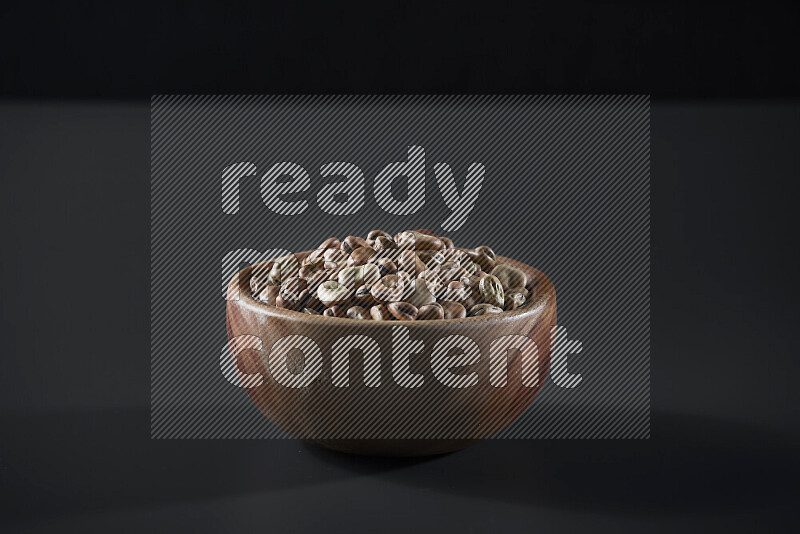 Fava beans in a wooden bowl on grey background