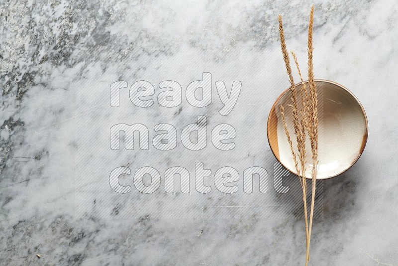 Wheat stalks on Multicolored Pottery Plate on grey marble flooring, Top view