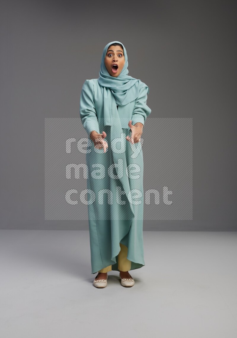 Saudi Woman wearing Abaya standing interacting with the camera on Gray background